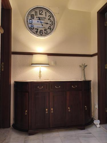 a clock on the wall above a wooden cabinet at Casa da Praça I in Amoreira
