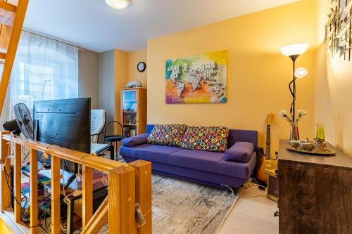 a living room with a purple couch and a tv at Good vibes house in Cres