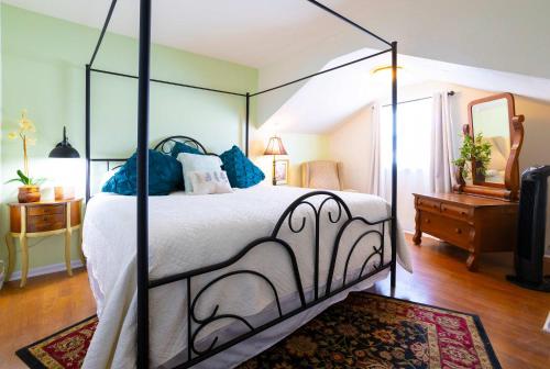 a bedroom with a large canopy bed with blue pillows at Mariposa Monarch - Walk to River in Kerrville