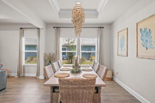 a dining room with a table with chairs and a chandelier at Beach House - Redfish Cove at Windmark Beach by Panhandle Getaways in Port Saint Joe