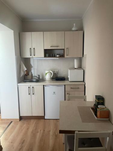 una cucina con mobili bianchi e un tavolo in una stanza di Butas Šventojoje a Šventoji