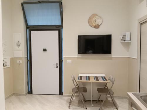 Zimmer mit Tür, Tisch und Stühlen in der Unterkunft Petit Maison in Castellammare di Stabia
