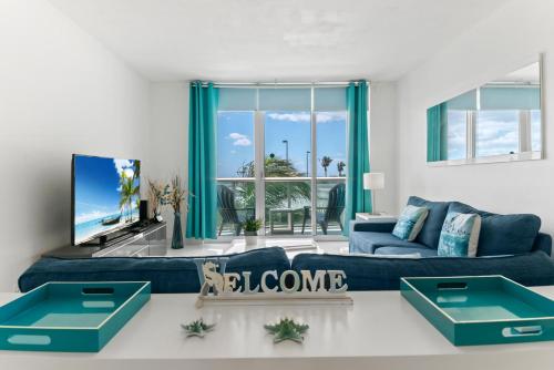 ein Wohnzimmer mit einer blauen Couch und einem Fernseher in der Unterkunft Ocean Wind - Luxury Beachfront Condo with Pool & Gym in Hollywood