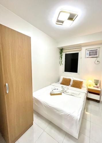 a bedroom with a large white bed and a window at Cozy 2BR Stay for 6pax in High-Floor, Wi-Fi & Family Games near IT Park Cebu- Unit Scarlett by GERRA in Mandaue City