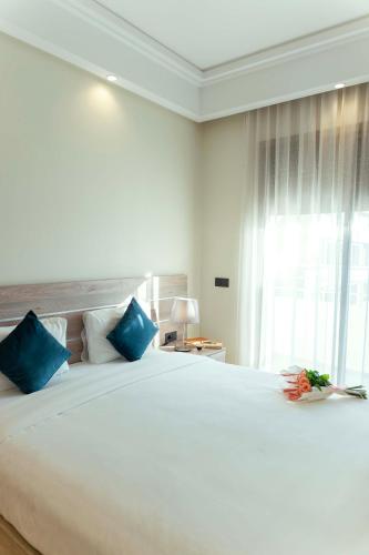 a bedroom with a large white bed with blue pillows at Flamant Rose Appart Hotel in Tangier