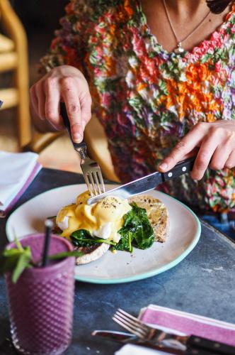 a woman holding a fork and knife and a plate of food at Artist Residence Cornwall in Penzance