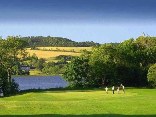 a group of people standing in a field next to a lake at Cois na hÉirne - Log Cabin I Lake View I Hot Tub in Belturbet