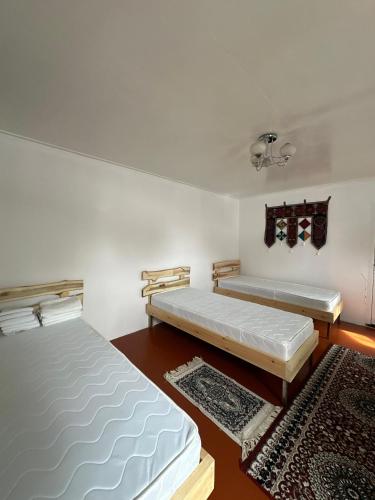 a bedroom with two beds and a rug at Kairat guest house in Kashkaldak