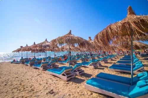 a group of blue lounge chairs and umbrellas on a beach at Vila Lasko Hotel in Golem