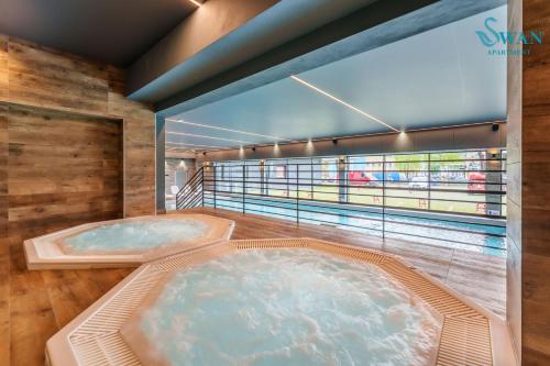 deux jacuzzis dans une pièce avec une fenêtre dans l'établissement SWAN Kołobrzeg Apartament KASPROWICZA 20C BASEN, SIŁOWNIA, BAWIALNIA - wszystko w cenie, à Kołobrzeg