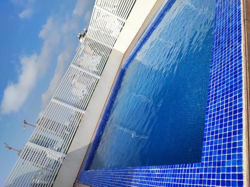 a building with blue tiles on the side of it at בריכה כחולה תחת שמיים כחולים מתאים למסיבות in Netanya