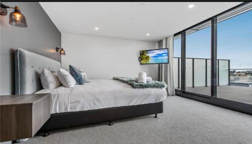 a bedroom with a large bed and a large window at Luxury Penthouse with Astonishing Bay and City Views in Melbourne
