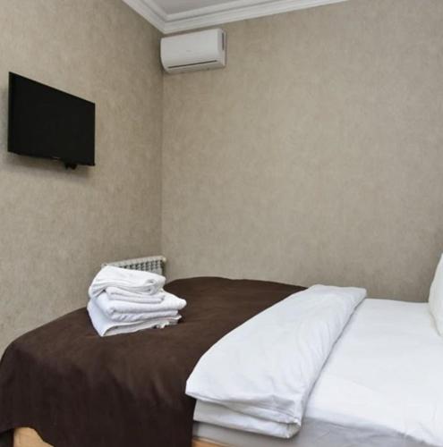 a bedroom with a bed with white sheets and a flat screen tv at Mehsul Recreational Center in İsmayıllı