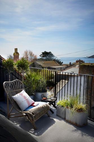 a chair on a balcony with a view of the ocean at Artist Residence Cornwall in Penzance