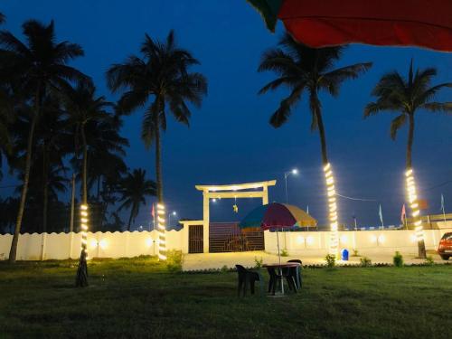 a house with palm trees and a gazebo at night at Home Away From Home in Tajpur