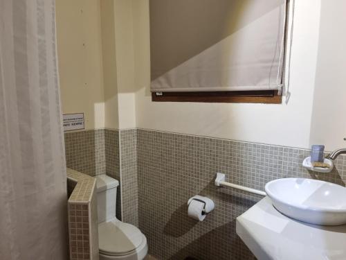 a bathroom with a white toilet and a sink at Boulevard 251 Riverside Apartments in Iquitos