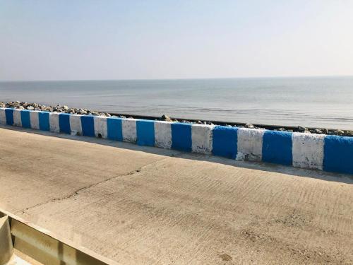 a long blue and white wall next to the ocean at Home Away From Home in Tajpur
