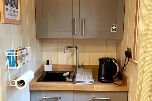 a kitchen counter with a sink and a microwave at Rustic 1BD Hut Retreat with Hot Tub & Countryside in Gedney