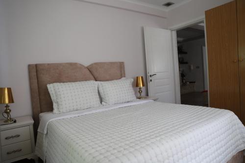 a bedroom with a large white bed with two pillows at Shtepi Pushimi Alesjo in Korçë