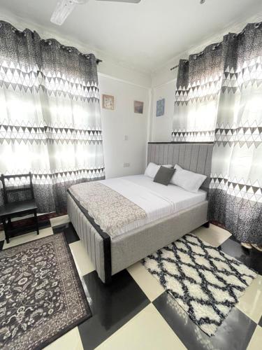 a bedroom with a bed and curtains and a chair at Studio apartment Mwenge in Dar es Salaam