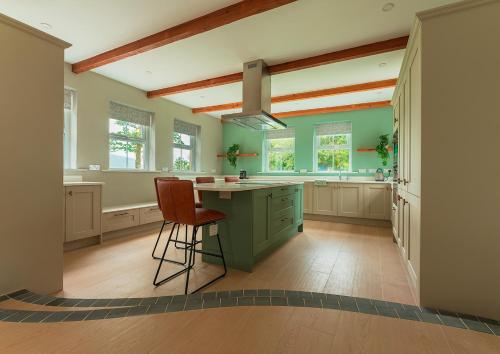 a kitchen with green cabinets and a island with chairs at Moneen Mountain View in Kinlough