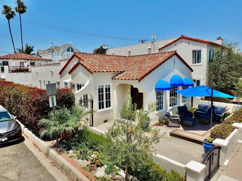 a white house with blue umbrellas in a yard at Belmont Shore Beach House - Incredible Oceanfront Views in Long Beach