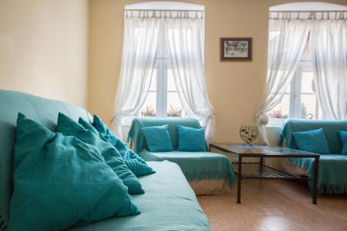 een woonkamer met twee blauwe banken en twee ramen bij Apartament Plaża in Gdańsk