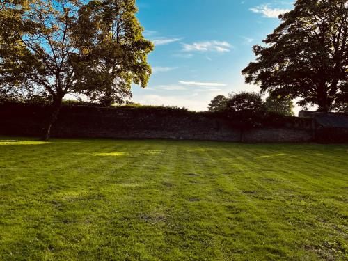 a field of grass with a fence and trees at Hut in the hall in Bedale