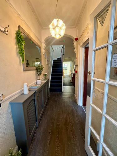 a hallway with a staircase and a chandelier at Rembrandt Guest House in Great Yarmouth