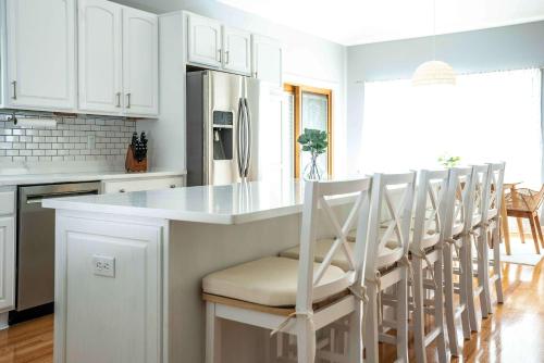a kitchen with white cabinets and a kitchen island with chairs at Maplewood Manor - Chic 6 BDR Downtown Walworth in Walworth