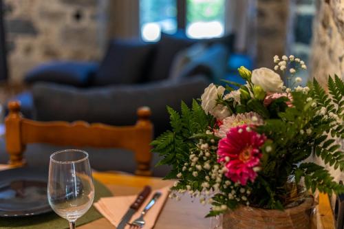 a table with a vase of flowers and a wine glass at Alsalos Apartment in Kardamili