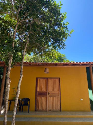 a yellow house with a door and two trees at Chalés Borborema Cumuru in Prado