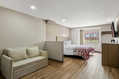 a living room with a couch and a bed at Red Roof Inn & Suites Euless - DFW Airport Southwest in Euless
