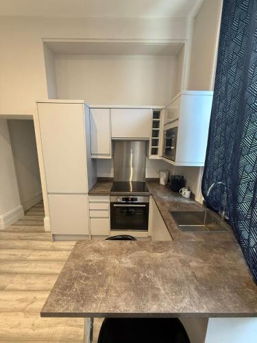 a kitchen with white cabinets and a stove top oven at Bolton Road Apartments in Eastbourne