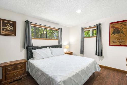 a bedroom with a white bed and two windows at Boondock Bliss - Lakefront with Private Dock Sleeps 15 in Sunrise Beach