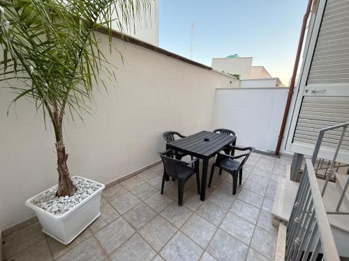 a patio with a table and chairs and a potted tree at Leo Rooms & Sea in Torre San Giovanni Ugento