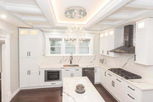 a white kitchen with white cabinets and a chandelier at 4 BDR Lake Geneva Estate Across from Beach in Lake Geneva