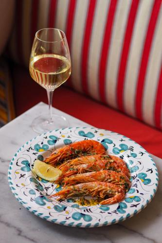 a plate of shrimp with a glass of wine at Artist Residence London in London