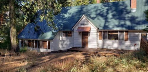 a white house with a blue roof at CC Cabin - Full Game Room & Wrap Around Deck in Shaver Lake