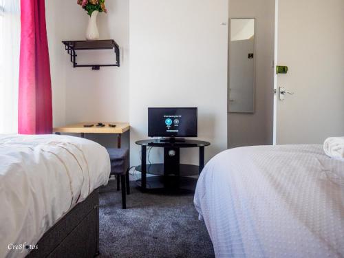 a room with two beds and a table with a television at Cornwallis House in Stoke on Trent