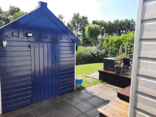 a blue shed with a door in a yard at Chalet V14 4pers in Makkum