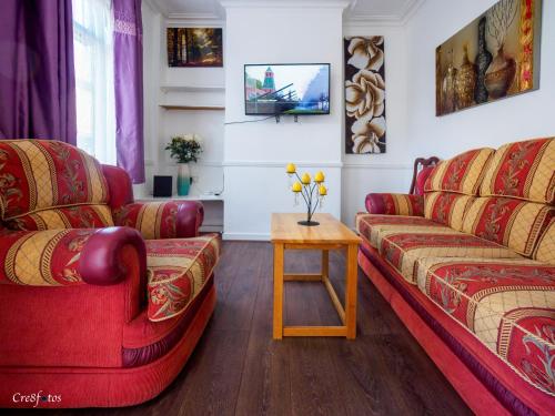 a living room with two red couches and a table at Cornwallis House in Stoke on Trent
