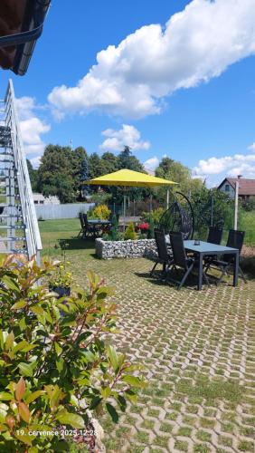a patio with a table and a yellow umbrella at Apartmány Kohoutek a Slepička v Novohradských horách in Nové Hrady