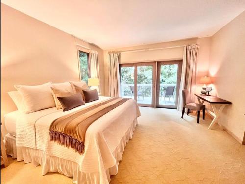 a bedroom with a large bed with a desk and windows at Spacious 4 BDR Home in Desirable Abbey Springs in Lake Geneva