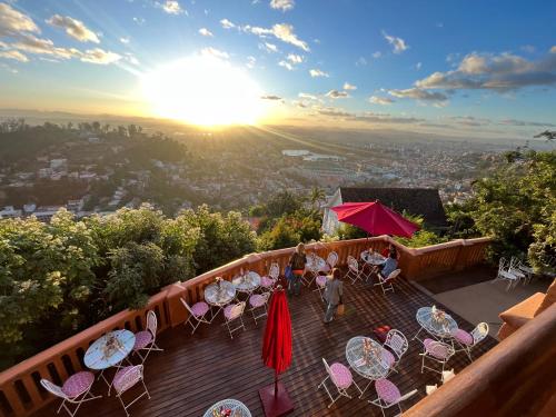 a balcony with tables and chairs and the sunset at Lokanga Boutique Hotel in Antananarivo