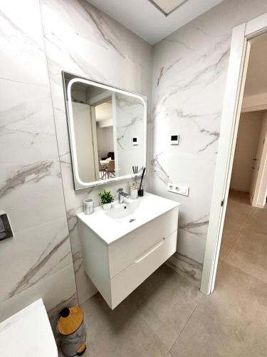 a white bathroom with a sink and a mirror at Camporosso Serpentine Duplex in Finestrat