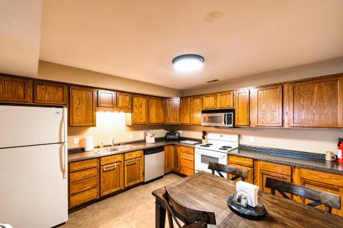 a kitchen with wooden cabinets and a table and a refrigerator at Osage Beach Getaway - Lake Views & Pet Friendly in Osage Beach