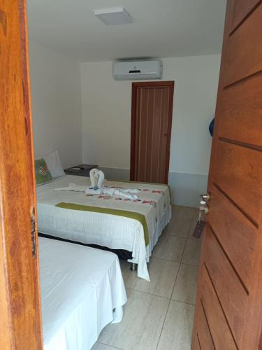 a bedroom with two beds with white sheets and a door at Pousada Algas Marinhas in Mangue Sêco