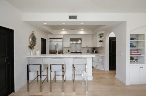 a kitchen with a white counter and stools at Poinsettia Palms - Chic & Luxe Patio Near Beach in Corona del Mar