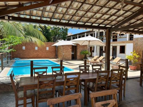 a patio with a table and chairs and a pool at Pousada Algas Marinhas in Mangue Sêco